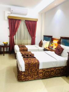 达卡Hotel West Valley Dhaka的配有红色窗帘的酒店客房的两张床