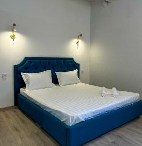 阿斯塔纳Astina Hotel的一张蓝色的床,上面有白色的床单和白色的鞋