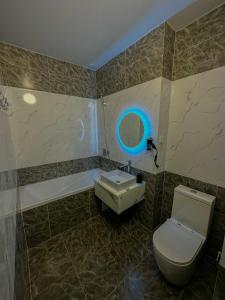 阿斯塔纳Astina Hotel的浴室设有卫生间和蓝光水槽。