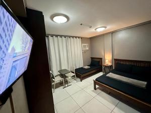 马尼拉Inn De Avenida, Makati的一间卧室配有一张床和一台平面电视