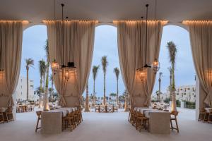 赫尔格达Serry Beach Resort的一个带桌椅和棕榈树的宴会厅