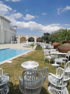 圣埃拉莫因科莱B&B Le Torri的一组白色的椅子和桌子,旁边是游泳池
