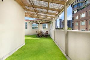 悉尼VENUS Harbourside - FEMALE ONLY HOSTEL的阳台拥有绿色的草地和桌椅