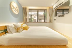 杭州梅开小筑客栈的窗户客房内的一张大白色床