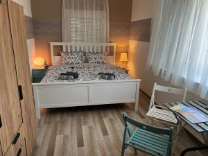 凯斯特海伊Szarkafészek的卧室配有白色的床和绿色椅子