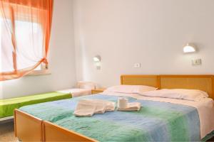 里米尼Hotel Gialpina的一间卧室配有两张床,床上配有两条毛巾