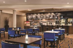 索尔兹伯里索尔兹伯里万怡酒店的一间带桌子和蓝色椅子的餐厅和一间酒吧