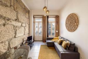 波尔图Wine Apartments的带沙发和石墙的客厅