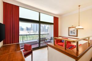 多哈喜来登超豪华度假会议酒店的酒店客房设有一张书桌和一个大窗户。