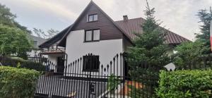 纳文丘夫Różana 4的白色的房子,有黑色的围栏