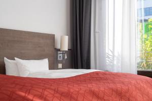 纽伦堡艺术商务酒店的一间卧室配有一张带红色毯子的床和窗户。