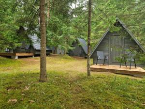 RõmedaLiivakõrtsi kämping的树林中的小屋,设有甲板和长凳