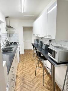 考文垂Modern Town House - Coventry的厨房配有白色橱柜和带微波炉的台面。