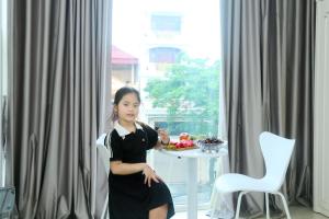 河内Noi Bai Ville Airport Hotel的坐在桌子前椅子上的年轻女孩