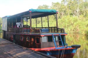 庞卡兰布翁Orangutan Kelotok Houseboat for 6 person的船停靠在码头旁