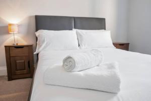 德比Glovers Lodge - Charming 3 Bed Retreat near City Centre的一张带毛巾的白色床,配有床头柜