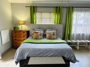 萨比萨比自助公寓的一间卧室配有一张带绿色窗帘的床和窗户。