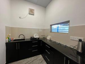亭可马里Aara Holiday Home的厨房配有黑色橱柜、水槽和窗户。