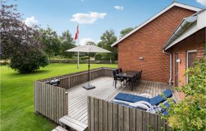 霍耶Stunning Home In Hjer With Wifi的木甲板配有桌子和遮阳伞