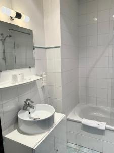 安纳马斯Hôtel Du Centre Annemasse的白色的浴室设有水槽和浴缸。