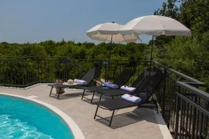 贝尔韦代雷Villa Tatai Country House by Dimore Trinacria的游泳池旁的甲板上配有椅子和遮阳伞