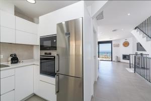 托雷德本纳贾尔邦WintowinRentals New and Sea View的厨房配有白色橱柜和不锈钢冰箱