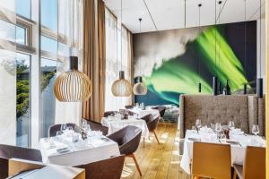 阿克雷里Akureyri - Berjaya Iceland Hotels的餐厅设有白色的桌椅和绿色的墙壁