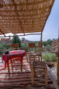 El KariaAgafay, La Ferme Nomade Bivouac的茅草屋顶天井上的两把椅子和一张桌子
