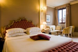 威尼斯萨赛格雷多酒店的卧室配有一张白色的大床和一张沙发。