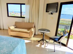 恩卡纳西翁De La Costa Hotel的客厅配有沙发、椅子和电视
