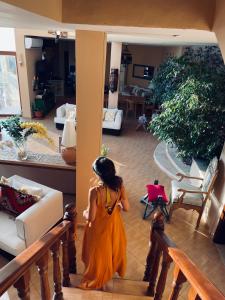 索瓦马The Precious Guesthouse的穿橙色衣服的年轻女孩在客厅里散步