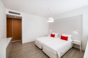 阿尔沃尔阿尔沃图瑞斯提克斯酒店的白色卧室配有2张白色的床和红色枕头