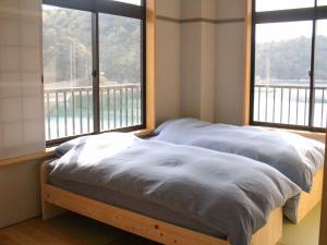 Ōdakazeto的一张位于带两个大窗户的房间的床铺