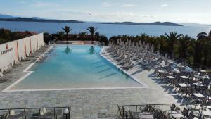 欧拉努波利斯Aristoteles Holiday Hotel And Spa的一个带椅子的游泳池,背景是大海
