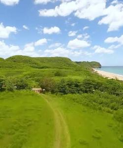 伊莎贝拉Villa Del Carmen Family Vacation Home的海滩旁的绿色山丘,有一条土路