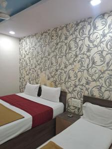 艾哈迈达巴德Hotel Gitanjali的一间卧室设有两张床,墙上贴有壁纸。