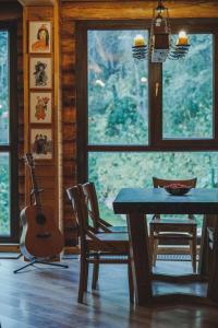 阿拉木图Sabay Sai Wooden Guesthouse in The National Park的小屋内带桌子和吉他的餐厅