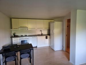 卑尔根Apartment 7 min from the airport的厨房配有白色橱柜和黑色桌椅