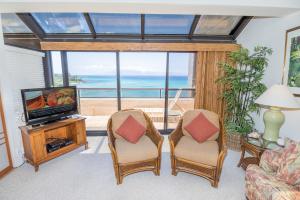 卡哈纳Sands Of Kahana 384 condo的一间配备有电视和椅子的客厅,享有美景。