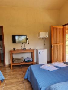 瓦尔任博尼塔Pousada Águas da Canastra的一间卧室设有两张床,墙上配有电视。