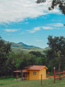 瓦尔任博尼塔Pousada Águas da Canastra的田间中的一个黄色小房子