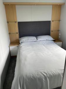 滨海克拉克顿Kingfisher Quay Lodge的一间卧室配有一张带白色床单和木制橱柜的床。