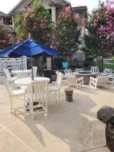 夏洛特South Charlotte’s Cozy & Modern的庭院配有白色的桌椅和蓝色的雨伞。