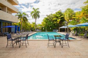 迈阿密Regency Miami Airport by Sonesta的毗邻度假酒店的带桌椅的游泳池