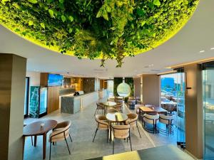 卡萨米尔Nobbu Hotel Ksamil的餐厅设有桌椅,天花板上种有植物