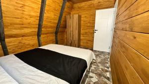 特拉布宗Kartal Yuvası Tatil Köyü的木制客房内的一间卧室,配有一张床