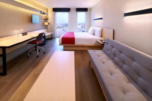 蒙特雷City Express by Marriott Monterrey Universidad的酒店客房配有一张床、一张书桌和一张沙发。