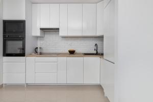 格但斯克Apartment Przytulna Kiełpinek by Renters的白色的厨房配有水槽和微波炉