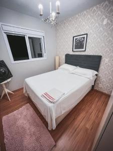 圣保罗Allianz Parque , Perdizes的卧室配有一张带吊灯的大型白色床。