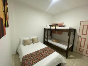 萨兰托Mahalo Hostel的一间卧室配有一张床和一张双层床。